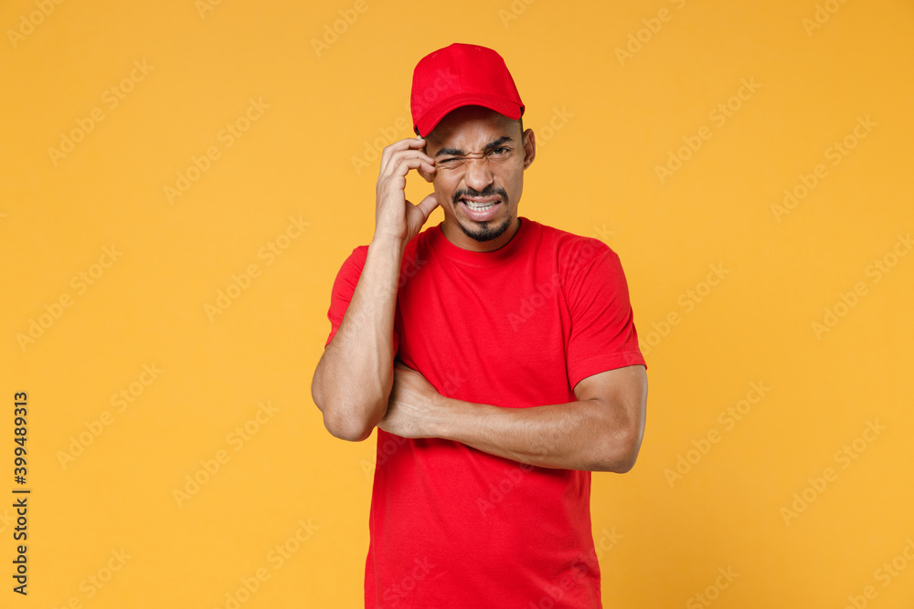 Delivery employee african man in red cap blank print t-shirt uniform workwear work courier service on quarantine covid-19 virus concept isolated on yellow background studio. Tattoo translation life.