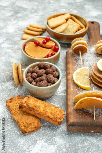 Simple pancakes with lemons on cutting board and cookies on blue background stock image