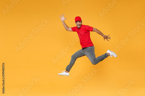 Full length fun delivery employee african man in red cap blank print t-shirt uniform workwear work courier dealer service on covid-19 virus concept jump run walk isolated on yellow background studio.