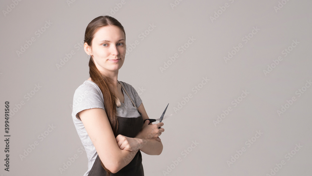 Naklejka premium Hairdresser holding scissors at gray studio background