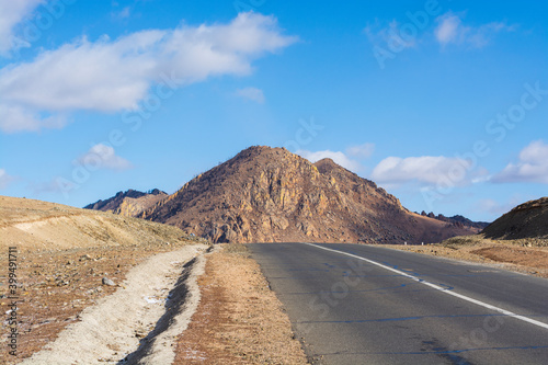 A beautiful mountain road without people and cars on a sunny day, a stunning landscape and an exciting way for car enthusiasts. The road on which you want to go forever, Mongolia