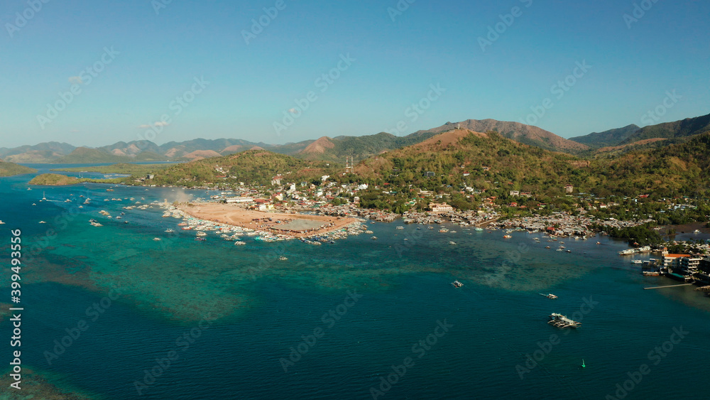 aerial view Coron City, tourist destination in the Philippines.Pier and promenade Coron town with boats on Busuanga island. Wooden boats waiting at pier. Seascape with mountains. Philippines, Palawan