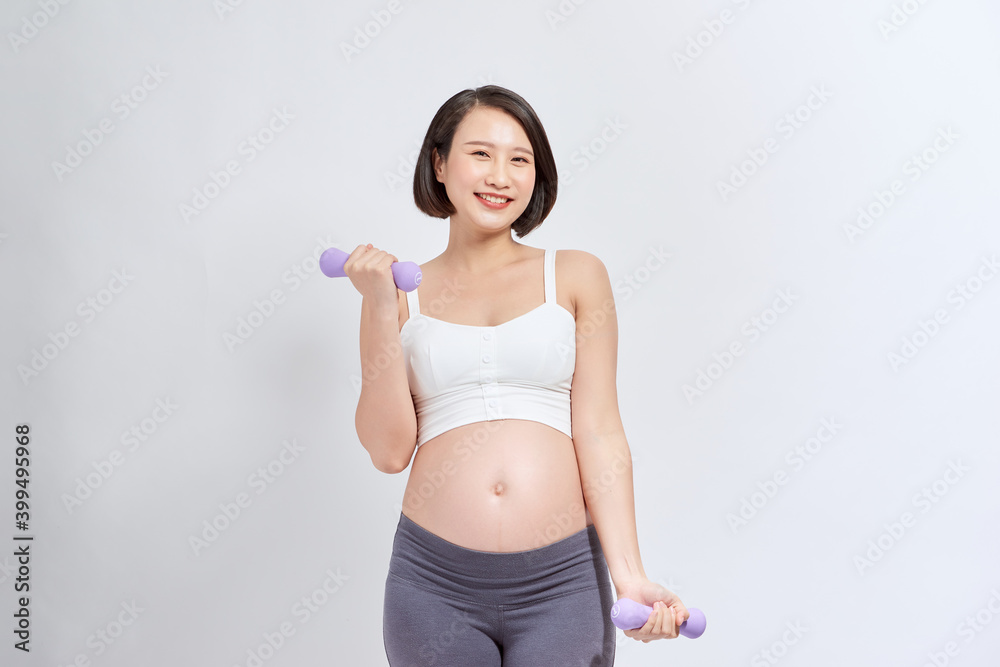 Pregnant woman exercising with dumbbells , isolated on white