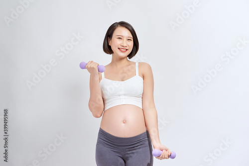 Pregnant woman exercising with dumbbells , isolated on white
