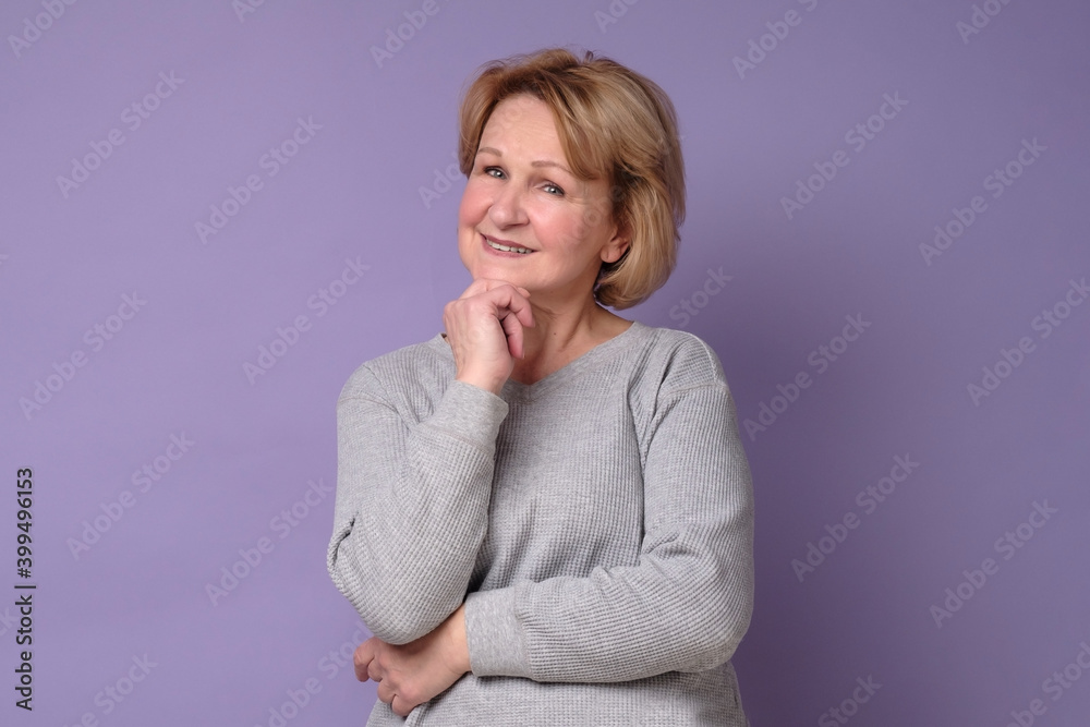Elderly woman standing smiling at the camera with hand on chin. Studio shot Elderly woman standing smiling at the camera with hand on chin. Studio shot