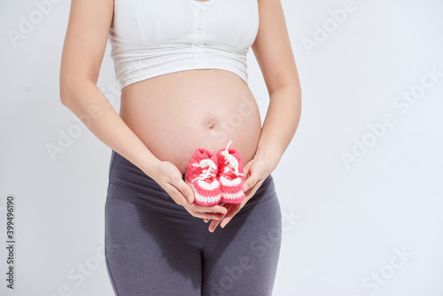 Small shoes for the unborn baby in the belly of pregnant woman