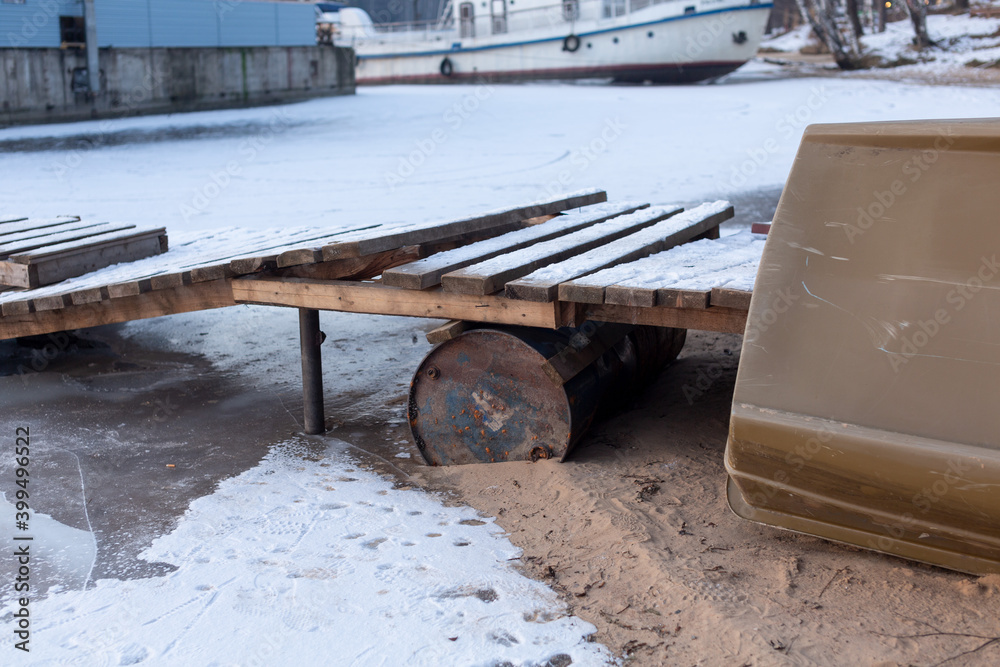 iron barrel under a wooden bridge over a frozen river