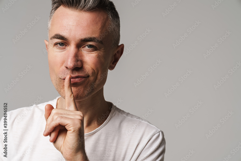 Serious man with finger on lips keeping a secret Serious man with finger on lips keeping a secret