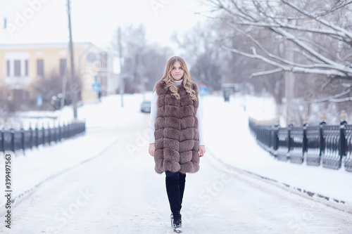girl in a fur vest walks in the winter outside / adult young model in winter clothes fur © kichigin19