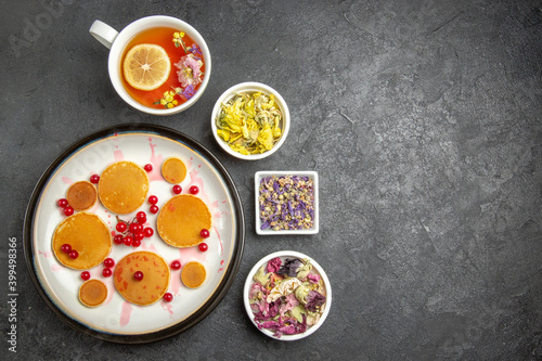 top view yummy pancakes with cup of tea on a dark background sweet pie dessert cake