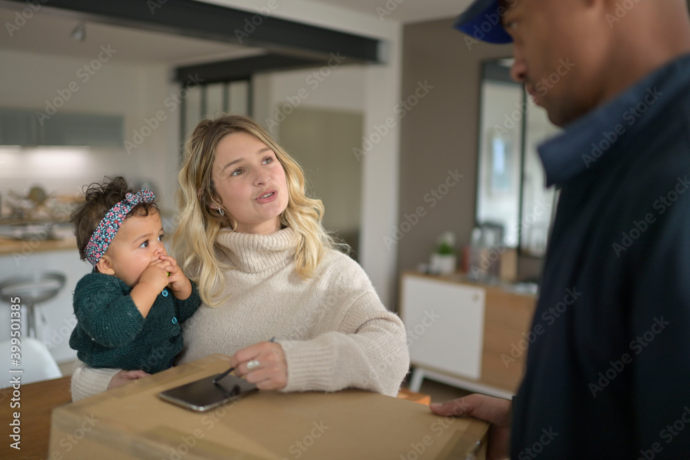 Woman with baby girl in arms signing package delivery receipt Woman with baby girl in arms signing package delivery receipt