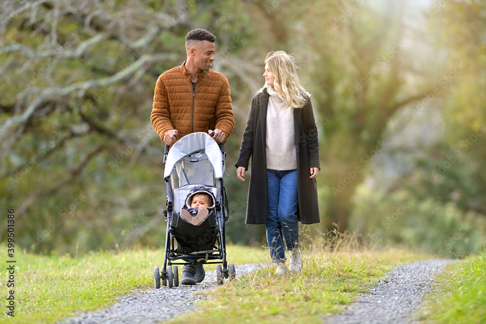 Fototapeta premium Couple with baby in stroller, walking outside in countryside
