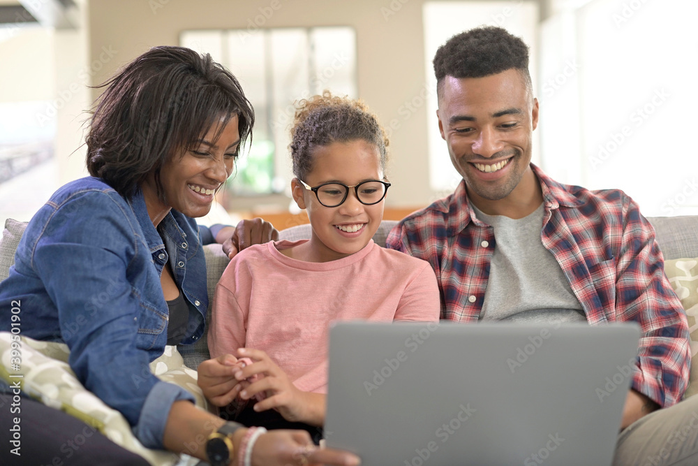 Happy family of three connected with laptop to communicate with relatives Happy family of three connected with laptop to communicate with relatives