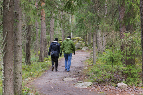A man and a woman are walking along a path in the forest