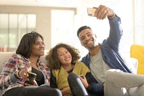 African-american family of three having fun playing with smartphones