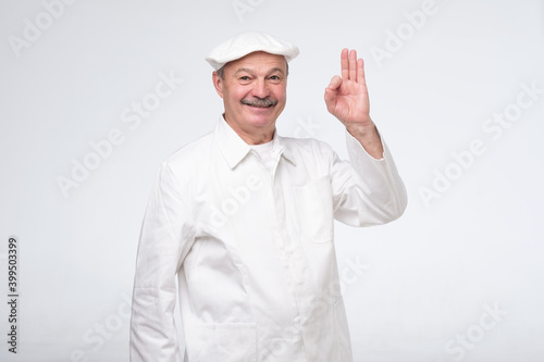 Elderly professional chef man showing ok gesture. Studio shot