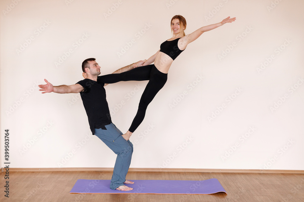 Fototapeta premium Couple trains yoga in the studio