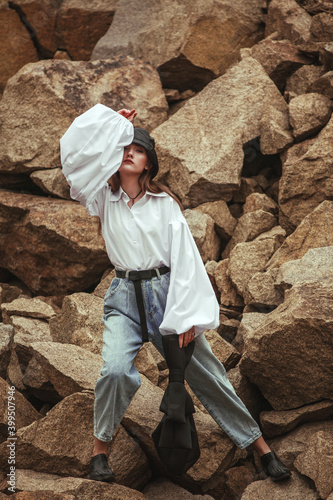 Stylish young woman model high fashion outdoors on background of stones and rocks, clothing conceptual portrait