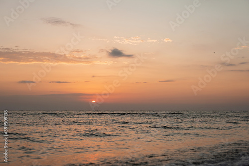 Colorful sunset on a sandy beach, waves with foam on the sand. Ocean, coast. Soft selective focus.