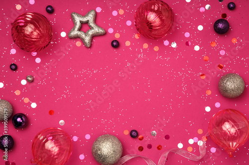 Christmas and New Year composition. Christmas glass decorations on a pink background sprinkled with glitter. Flat layer, top view, copy space