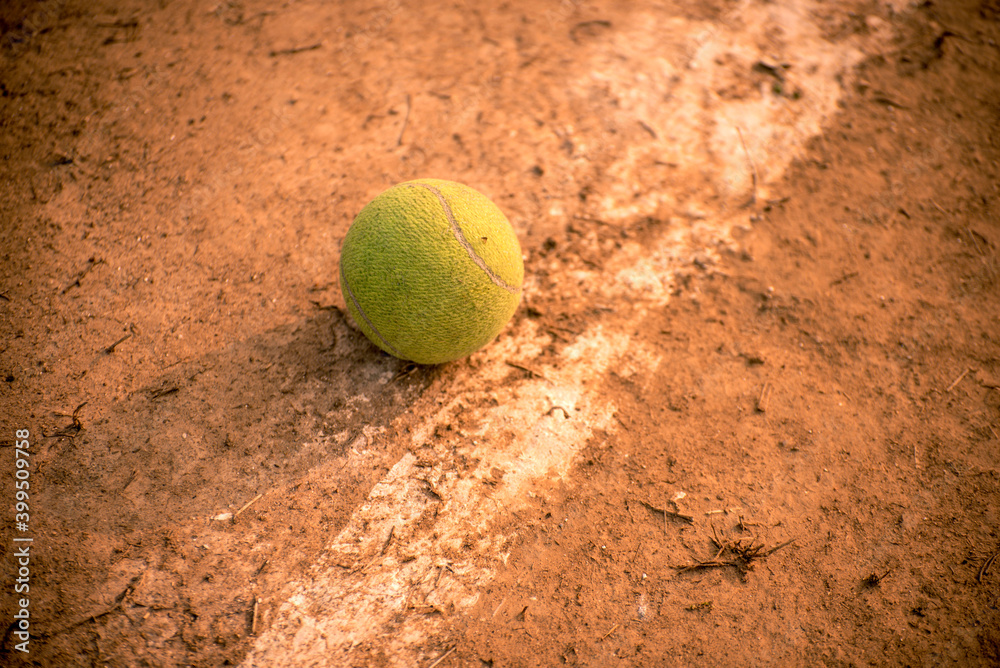 Close-up of tennis ball on clay court on the side line.