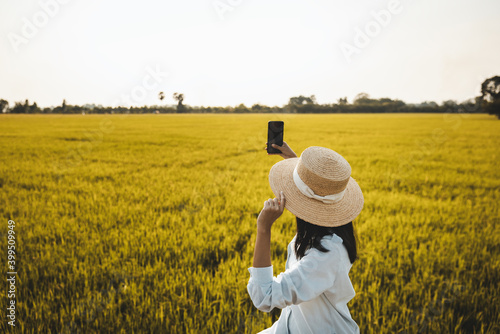Traveler woman using mobile phone on rice field farm in Thailand