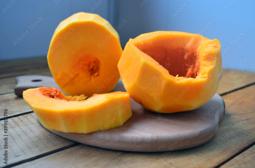 Sliced ​​orange pumpkin on a wooden board. Fresh vegetables without skin. Pieces.