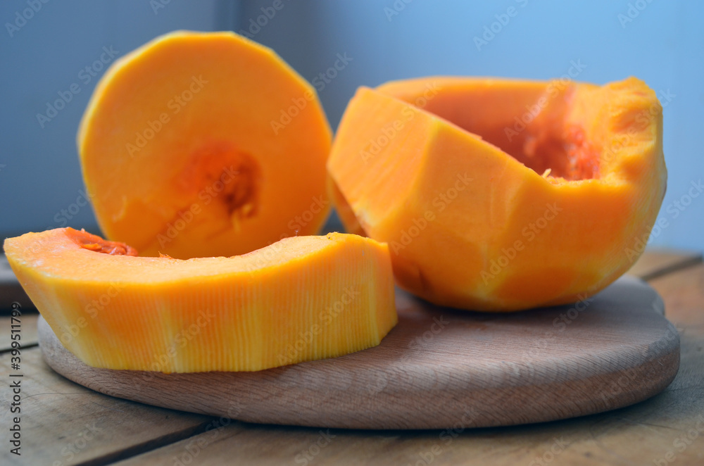 Sliced orange pumpkin on a wooden board. Fresh vegetables without skin. Pieces. Sliced orange pumpkin on a wooden board. Fresh vegetables without skin. Pieces.