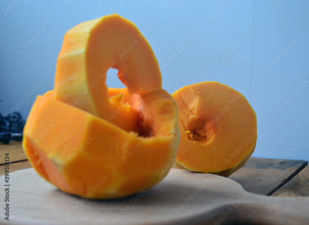 Sliced ​​orange pumpkin on a wooden board. Fresh vegetables without skin. Pieces.