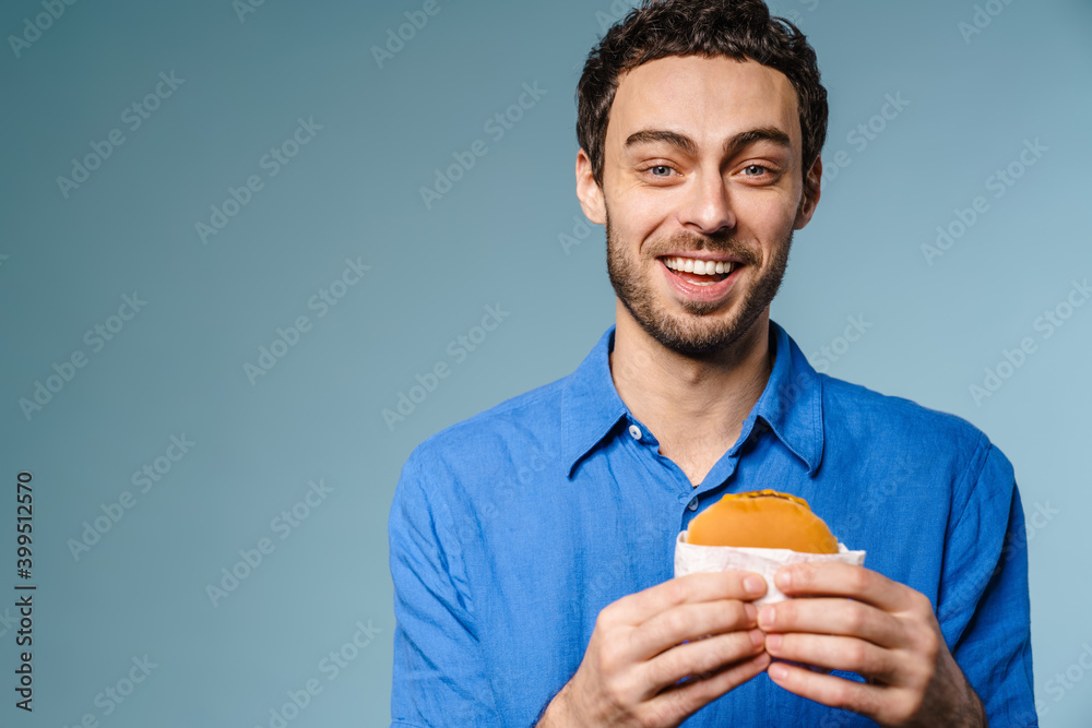 Joyful handsome guy smiling while posing with hamburger Joyful handsome guy smiling while posing with hamburger