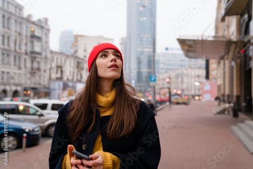 Charming caucasian girl looking upward while posing at city street