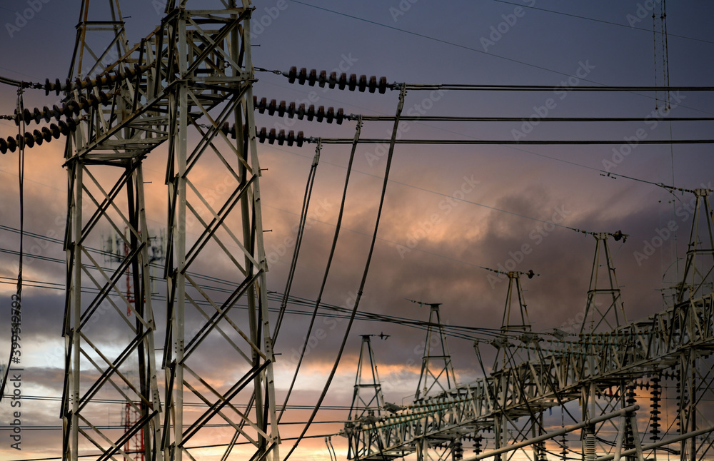 High voltage electric pylon and electrical wire against stormy sky and clouds. High voltage grid tower with wire cable. Transmission lines on high voltage grid tower. Three-phase electric power.
