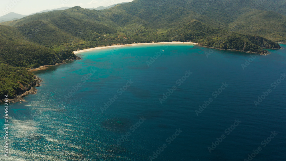 Aerial view beautiful tropical beach Nagtabon in the cove with blue lagoon and turquoise water surrounded by rainforest. Palawan, Philippines. tropical landscape. Seascape island and clear blue water