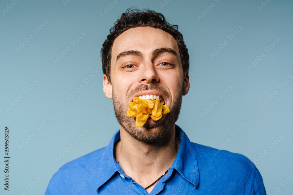 Happy handsome guy posing with french fries in his mouth Happy handsome guy posing with french fries in his mouth