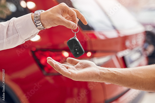 Crop customer receiving key of new car
