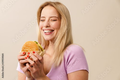 Cheerful beautiful girl laughing while posing with hamburger