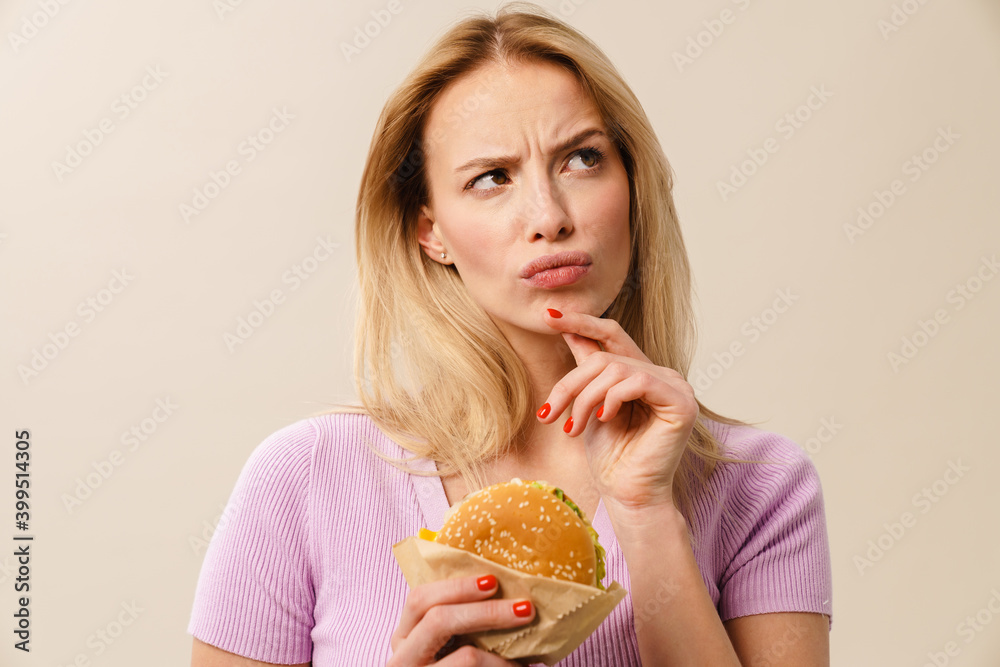 Brooding beautiful blonde girl posing with hamburger Brooding beautiful blonde girl posing with hamburger