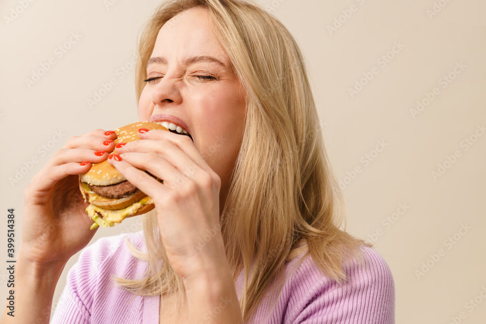 Happy beautiful hungry girl eating hamburger on camera