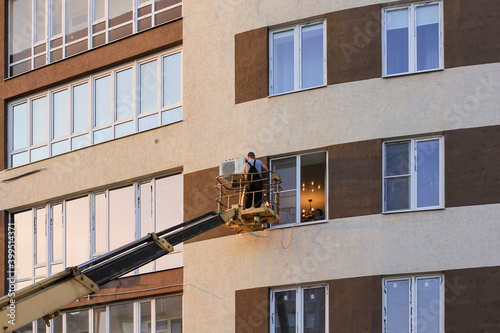 Industrial technician, engineer installing air conditioner on the facade of the house.