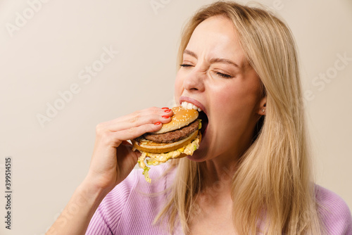 Excited beautiful hungry girl eating hamburger on camera