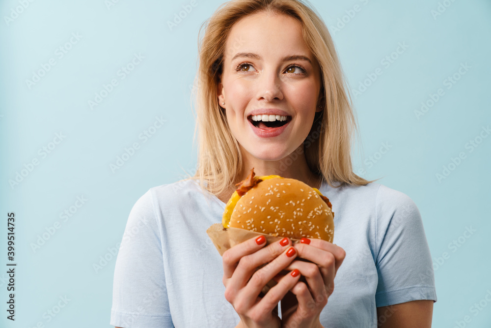 Cheerful beautiful girl smiling while posing with hamburger