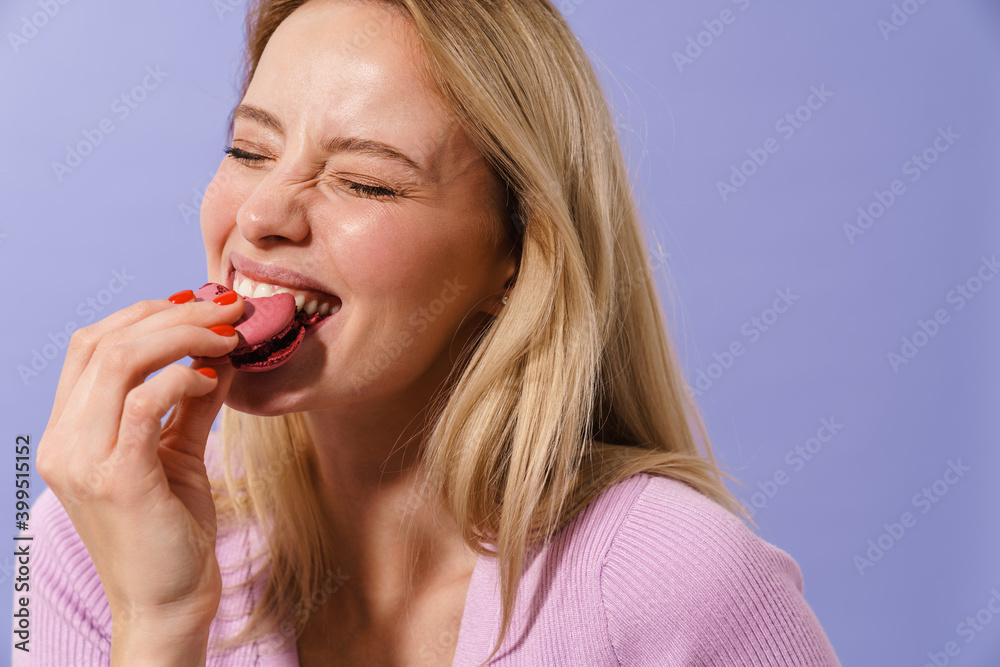 Cheerful beautiful girl laughing while eating macaroon