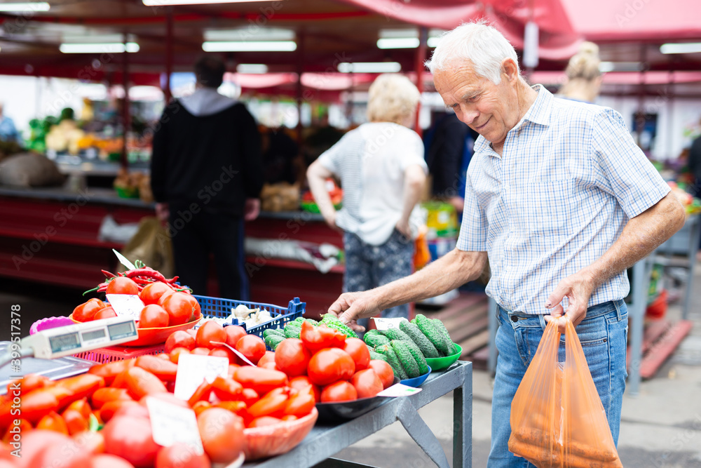 retired european man buying tomatoes in market