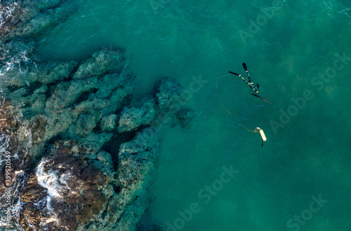 Aerial view at turquoise sea and Spearfishing diver with full equipment and speargun hunting near rocks