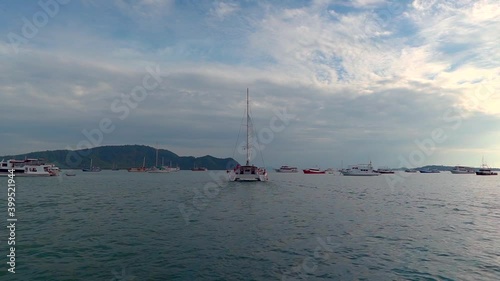 Yacht sailing out to the sea passing along many boat alongside