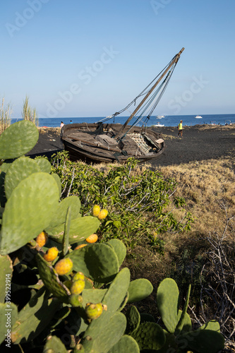 An old abandoned wooden boat on the black volcanic beach. the beauty of the boat remains intact even if tilted by ninety degrees, which helps to make the scenery even more impressive