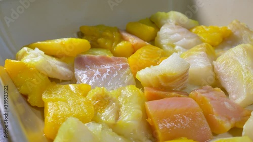 Closeup POV circular dolly shot of pieces of mixed raw fish – salmon, cod and smoked haddock - in an oven dish, forming the base ingredient for a meal to be baked. photo