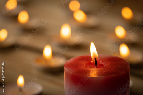 Candles on a wooden background. A red sick candle that changes color when you light it and small candles. Shallow depth of field.