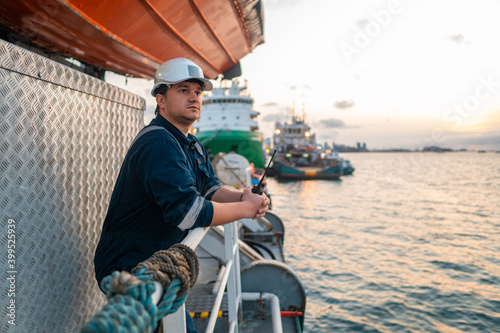 Marine Deck Officer or Chief mate on deck of offshore vessel or ship , wearing PPE personal protective equipment - helmet, coverall. Ship is on background