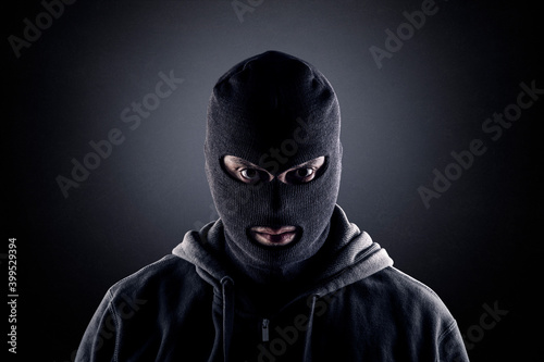 Canvas Print Criminal wearing black balaclava and hoodie in the dark